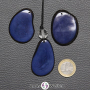 Drei Tagua-Nuss-Scheiben in Blau. Die mittlere ist mit einer Bergkristallkugel an ein schwarzes Baumwollband gebunden.