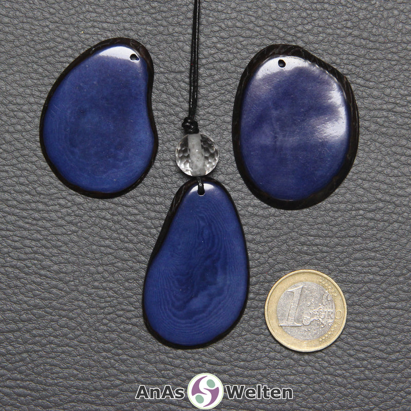 Drei Tagua-Nuss-Scheiben in Blau. Die mittlere ist mit einer Bergkristallkugel an ein schwarzes Baumwollband gebunden.