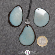 Drei Tagua-Nuss-Scheiben in Blau. Die mittlere ist mit einer Bergkristallkugel an ein schwarzes Baumwollband gebunden.