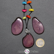Drei lila Tagua-Nuss-Scheiben. Eine ist mit einer Bergkristallkugel und 6 bunten Tagua-Splittern als Kette gebunden.