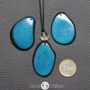 Drei Tagua-Nuss-Scheiben in Türkis. Die mittlere ist mit einer Bergkristallkugel an ein schwarzes Baumwollband gebunden.