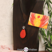 Ein roter Tagua-Nuss Engel Anhänger ist als Kette mit einer Bergkristallkugel um eine dunkle Büste gehängt.