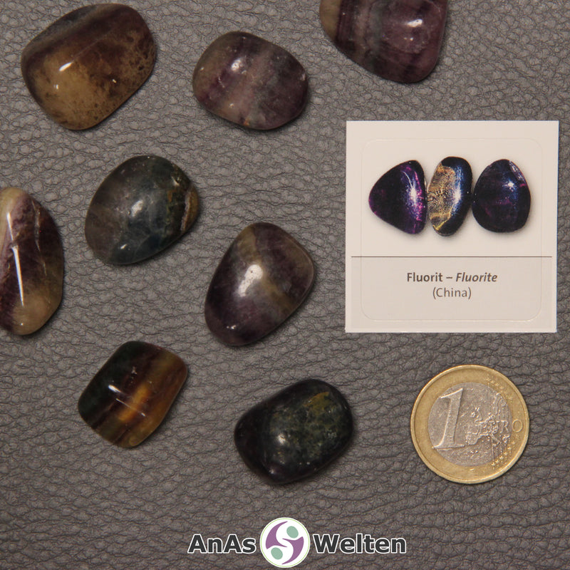 Mehrere Beispiele für den Fluorit Trommelstein. Daneben liegt der Sticker.