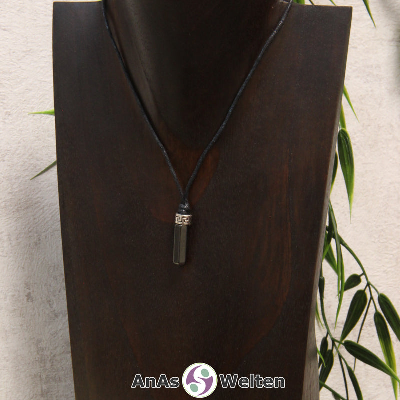 Eine dunkelgraue Hämatin Stift-Anhänger klein Kette mit einem Metallelement über dem Edelstein an einer hellen Büste.