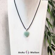 Ein Aventurin Herz Anhänger an einem schwarzen Baumwollband, der um eine helle Büste gehängt wurde.