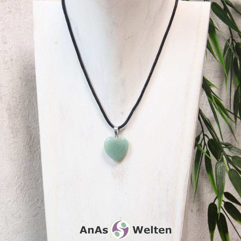 Ein Aventurin Herz Anhänger an einem schwarzen Baumwollband, der um eine helle Büste gehängt wurde.