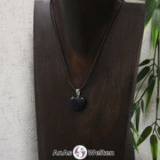 Ein Blaufluss Herz Anhänger an einem schwarzen Baumwollband, der um eine dunkle Büste gehängt wurde.