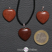 Drei Herzanhänger aus Goldfluss nebeneinander. Einer befindet sich an einem schwarzen gewachsten Baumwollband.