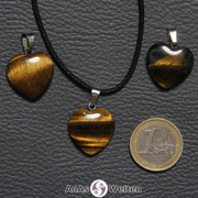 Drei Herzanhänger aus Tigerauge nebeneinander. Einer befindet sich an einem schwarzen gewachsten Baumwollband.