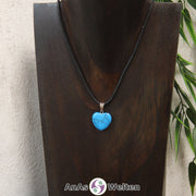 Ein Turquenit Herz Anhänger an einem schwarzen Baumwollband, der um eine dunkle Büste gehängt wurde.