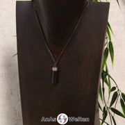 Eine schwarze Onyx Stift-Anhänger klein Kette mit einem Metallelement über dem Edelstein an einer hellen Büste.