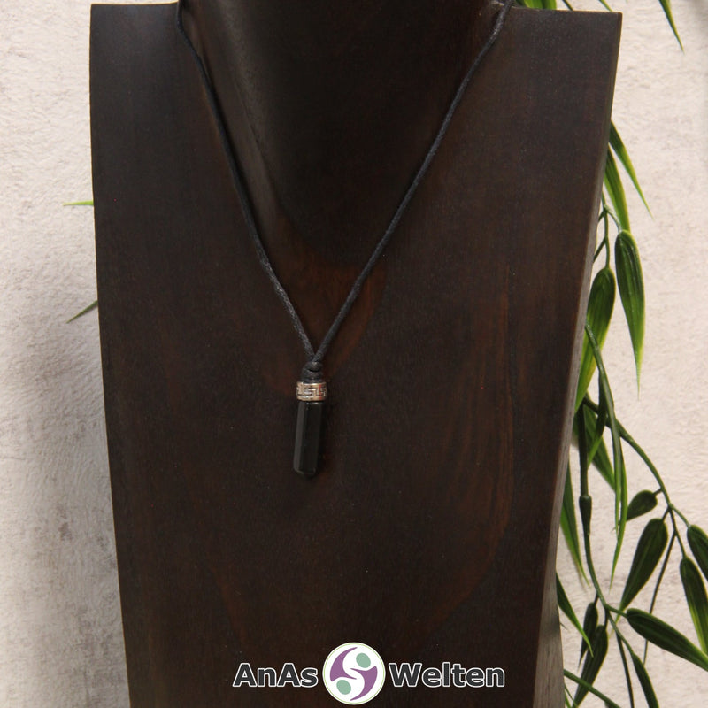 Eine schwarze Onyx Stift-Anhänger klein Kette mit einem Metallelement über dem Edelstein an einer hellen Büste.