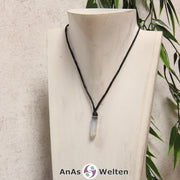 Eine durchsichtig blaue Fluorit Stift-Anhänger klein Kette mit einem Metallelement über dem Edelstein an einer dunklen Büste.