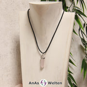 Ein Rosenquarz Stift-Anhänger groß mit Metallöse, der mit einem schwarzen Baumwollband um eine helle Büste gehängt wurde