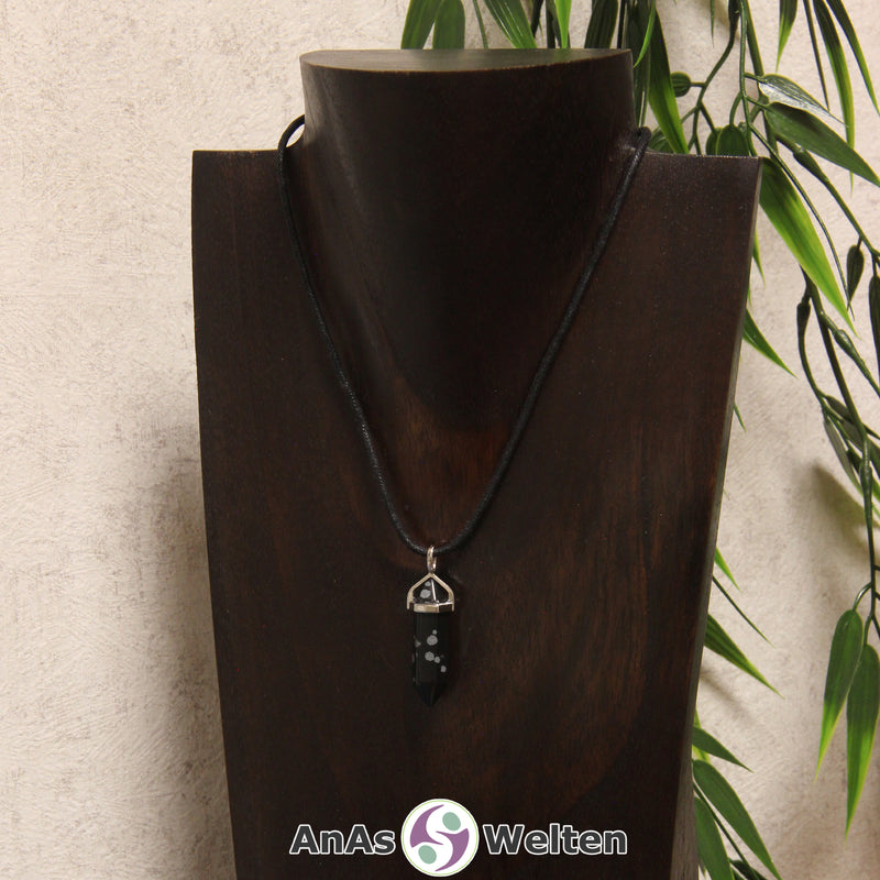 Ein Schneeflocken-Obsidian Stift-Anhänger groß mit Metallöse, der mit einem schwarzen Baumwollband um eine dunkle Büste gehängt wurde