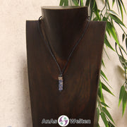 Eine weiß-blaue Sodalith Stift-Anhänger klein Kette mit einem Metallelement über dem Edelstein an einer dunklen Büste.