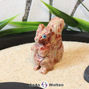 Das Bild zeigt ein Speckstein Eichhörnchen klein. Die Specksteinfigur steht auf den Hinterbeinen und sieht geradeaus. Das Fell am buschigen Schwanz sowie die Pfoten, Ohren und Schnauze sind mit Einkerbungen im Stein herausgearbeitet.