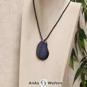 Eine hellblau gefärbte Tagua-Nuss Schmuck Kette mit Öse mit einem schwarzen Baumwollband an einer hellen Büste.