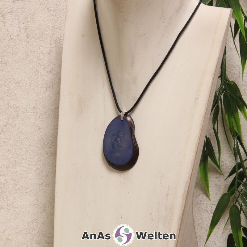 Eine hellblau gefärbte Tagua-Nuss Schmuck Kette mit Öse mit einem schwarzen Baumwollband an einer hellen Büste.