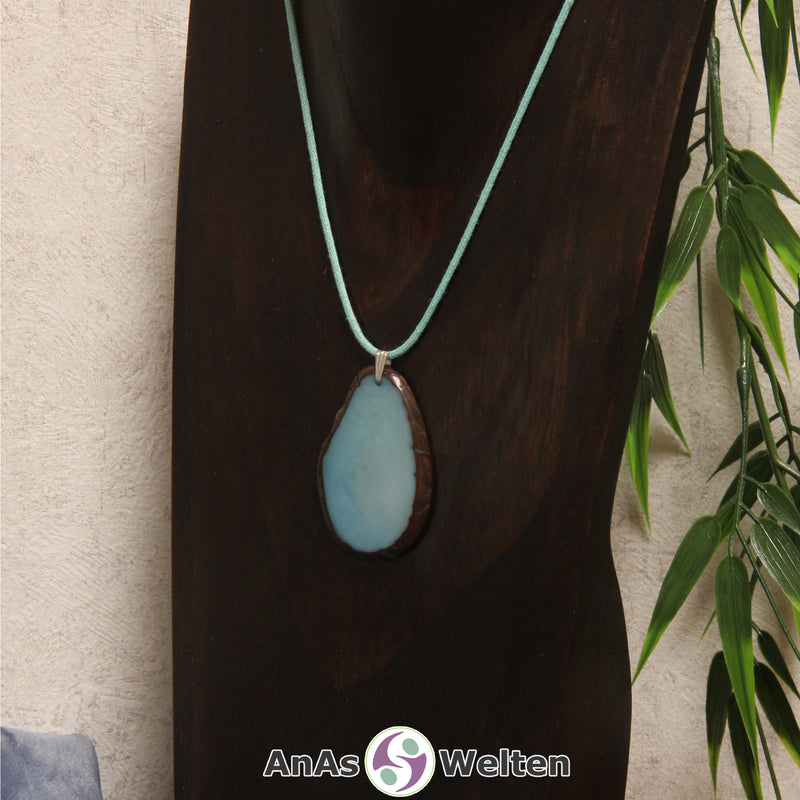 Eine himmelblaue Tagua-Nuss Schmuck Kette mit Öse mit einem türkisen Baumwollband an einer dunklen Büste.