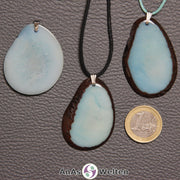 Drei himmelblaue Tagua-Nuss-Scheiben mit Metallöse. Zwei sind an einem schwarzen bzw. türkisen Baumwollband.