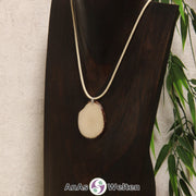 Das Produktbild zeigt die Tagua-Nuss-Schmuck Kette himmlblau. Zu sehen ist eine hellblaue Tagua-Nuss-Scheibe, die mit einer Edelstahlöse an einem beigen Baumwollband befestigt ist. Die Nuss-Scheibe hat einen dunklen Rand und eine glänzende Oberfläche.