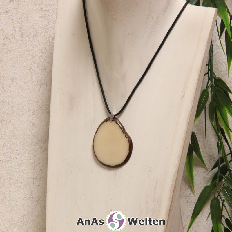 Eine naturfarbene Tagua-Nuss Schmuck Kette mit Öse mit einem schwarzen Baumwollband an einer hellen Büste.
