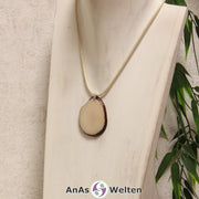 Eine naturfarbene Tagua-Nuss Schmuck Kette mit Öse mit einem beigen Baumwollband an einer hellen Büste.