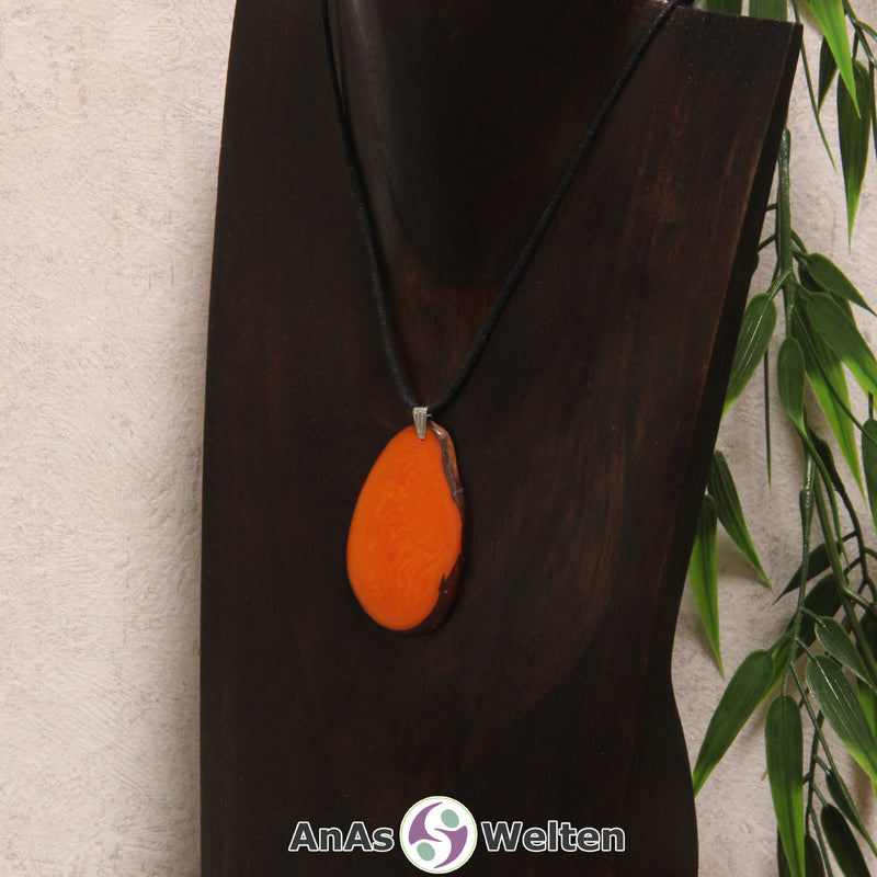 Eine orange gefärbte Tagua-Nuss Schmuck Kette mit Öse mit einem schwarzen Baumwollband an einer dunklen Büste.