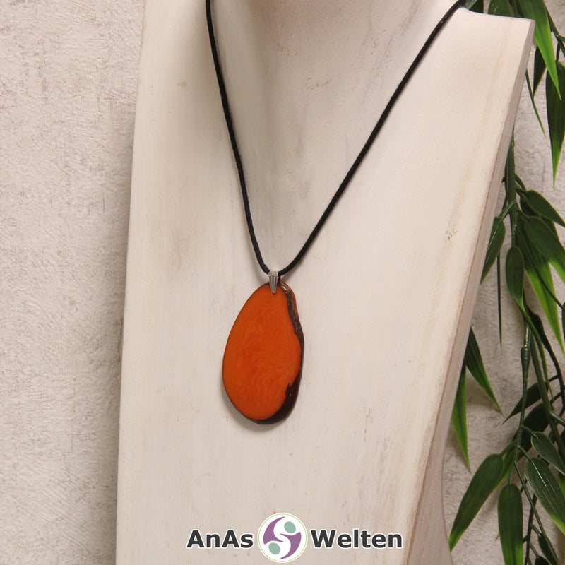 Eine orange gefärbte Tagua-Nuss Schmuck Kette mit Öse mit einem schwarzen Baumwollband an einer hellen Büste.
