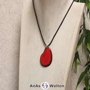 Eine rote Tagua-Nuss Schmuck Kette mit Öse mit einem schwarzen Baumwollband an einer hellen Büste.