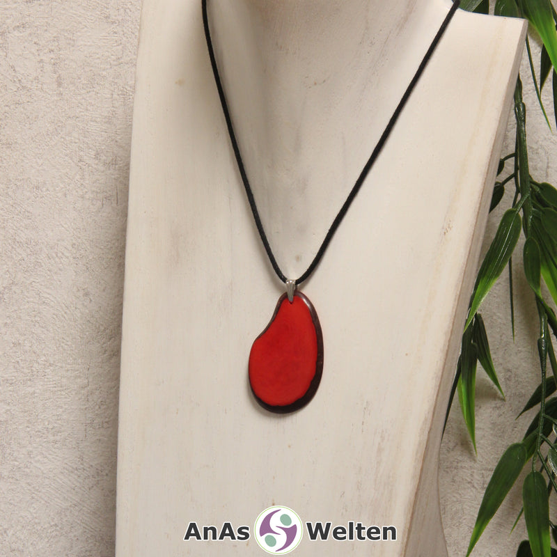 Eine rote Tagua-Nuss Schmuck Kette mit Öse mit einem schwarzen Baumwollband an einer hellen Büste.