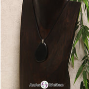 Eine schwarz gefärbte Tagua-Nuss Schmuck Kette mit Öse mit einem schwarzen Baumwollband an einer dunklen Büste.