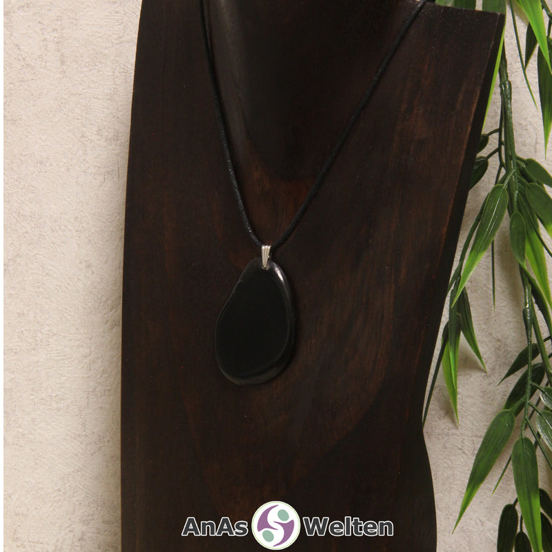 Eine schwarz gefärbte Tagua-Nuss Schmuck Kette mit Öse mit einem schwarzen Baumwollband an einer dunklen Büste.