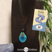 Eine türkis gefärbte Tagua-Nuss Sternzeichen Kette mit goldfarbenem Fische-Symbol und Lavakugel an einer dunklen Büste.