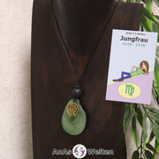 Eine grün gefärbte Tagua-Nuss Sternzeichen Kette mit goldfarbenem Jungfrau-Symbol und Lavakugel an einer dunklen Büste.