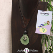 Eine grün gefärbte Tagua-Nuss Sternzeichen Kette mit silberfarbenem Jungfrau-Symbol und Lavakugel an einer dunklen Büste.