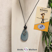 Eine himmelblau gefärbte Tagua-Nuss Sternzeichen Kette mit silberfarbenem Schütze-Symbol und Lavakugel an einer hellen Büste.