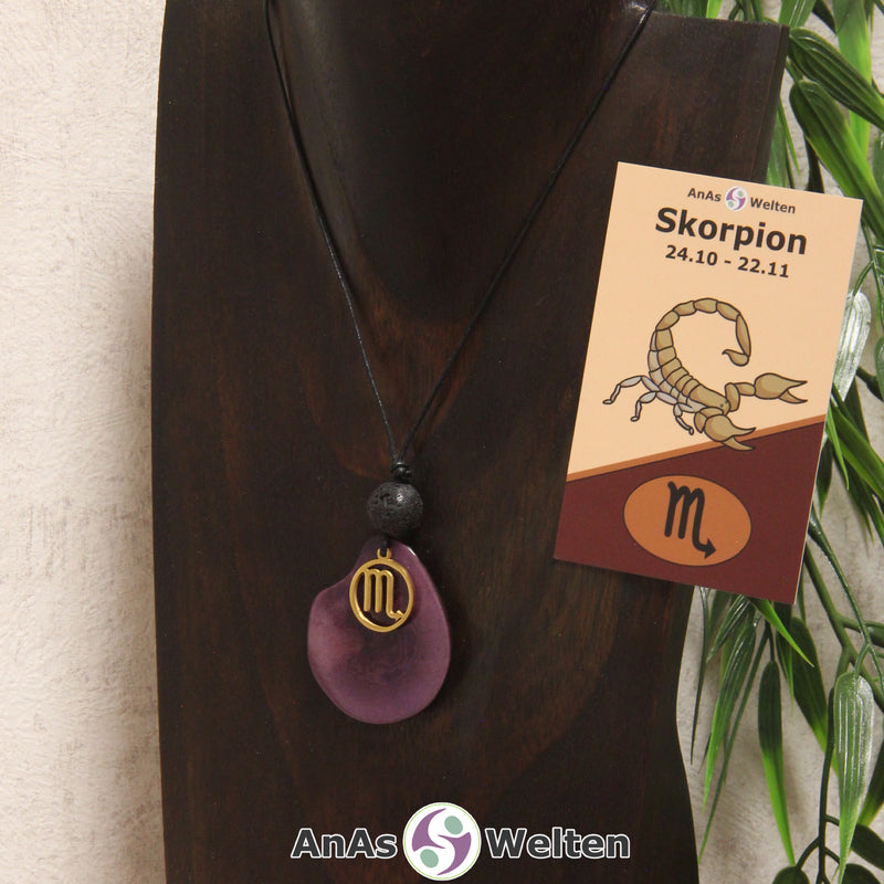 Eine violett gefärbte Tagua-Nuss Sternzeichen Kette mit goldfarbenem Skorpion-Symbol und Lavakugel an einer dunklen Büste.