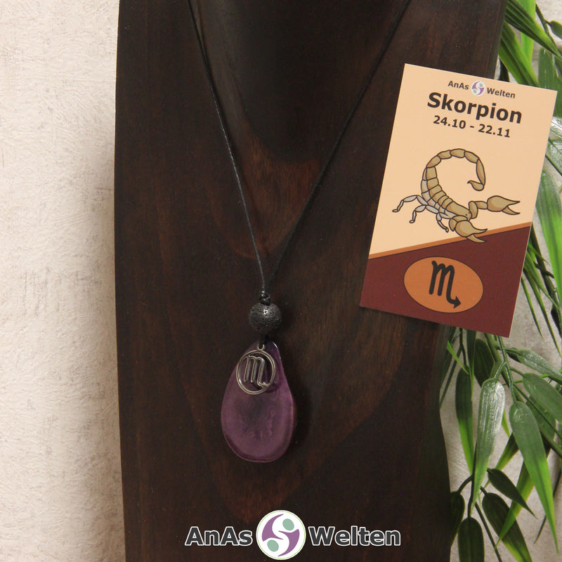 Eine violett gefärbte Tagua-Nuss Sternzeichen Kette mit silberfarbenem Skorpion-Symbol und Lavakugel an einer dunklen Büste.