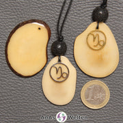 Drei Tagua-Nuss-Scheiben in beige. Zwei davon sind als Kette mit Lavakugel und Steinbock-Symbol gebunden.