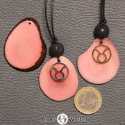 Drei Tagua-Nuss-Scheiben in rosa. Zwei davon sind als Kette mit Lavakugel und Stier-Symbol gebunden.