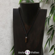 Eine braun schimmernde Tigerauge Stift-Anhänger klein Kette mit einem Metallelement über dem Edelstein an einer dunklen Büste.