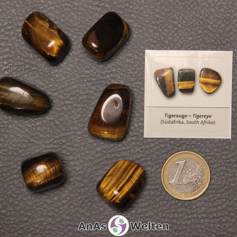 Mehrere Beispiele für den Tigerauge Trommelstein. Daneben liegt der Sticker.