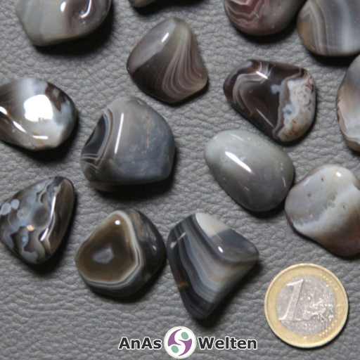 Das Bild zeigt mehrere Beispiele für den Achat Trommelstein. Man sieht gut die unterschiedlichen Musterungen der hauptsächlich gestreiften grauen, blaugrauen, braunen und graugrünen Steine.