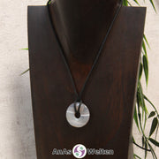 Das Bild zeigt einen Achat Donut an einem Baumwollband. Der Achat Donut ist grau-weiß-graublau gestreift.