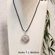 Ein Achat Donut an einem Donut-Halter Spirale, der mit einem gewachsten Baumwollband um eine helle Büste hängt.