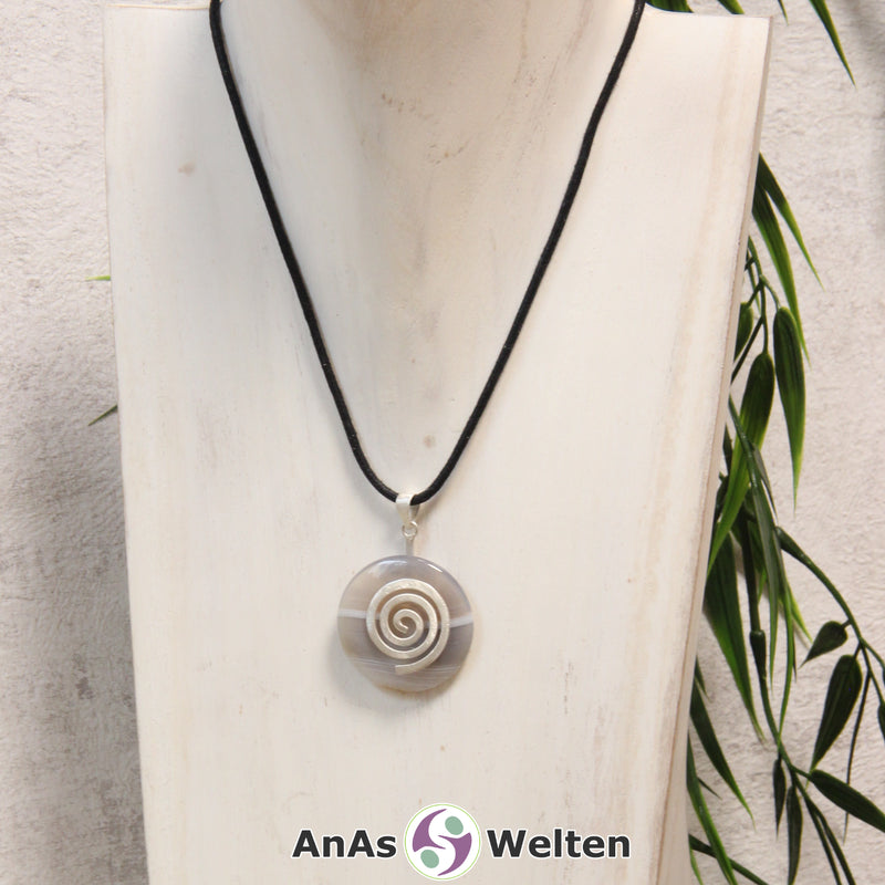 Ein Achat Donut an einem Donut-Halter Spirale, der mit einem gewachsten Baumwollband um eine helle Büste hängt.