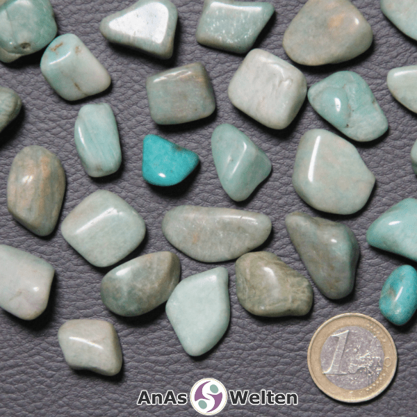Das Bild zeigt einen Amazonit Trommelstein in verschiedenen Variationen. Man erkennt hier gut die möglichen Farbunterschiede von einer fast weißen Hellblau über ein kräftiges Blaugrün bis hin zu einem Blaubraun.