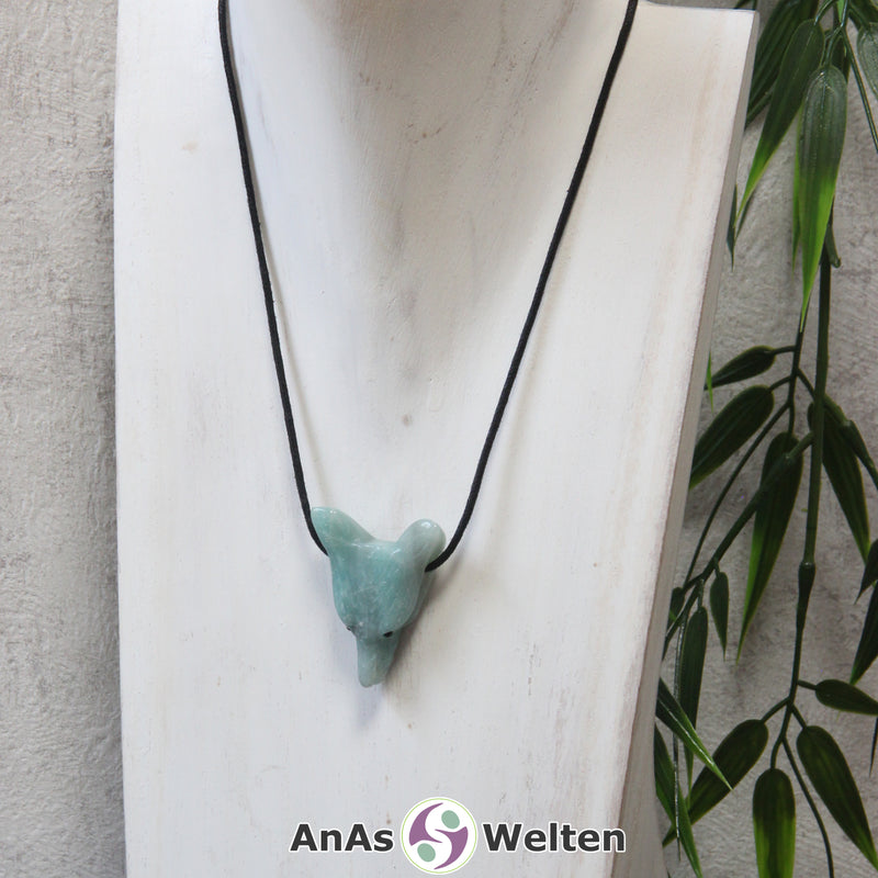 Ein Amazonit Wolf Anhänger an einem schwarzen Baumwollband, der um eine dunkle Büste gehängt wurde.